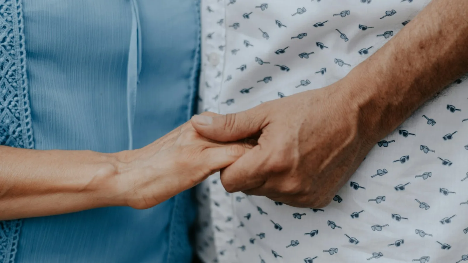 Main d'un aidant tenant la main d'une personne âgée dépendante