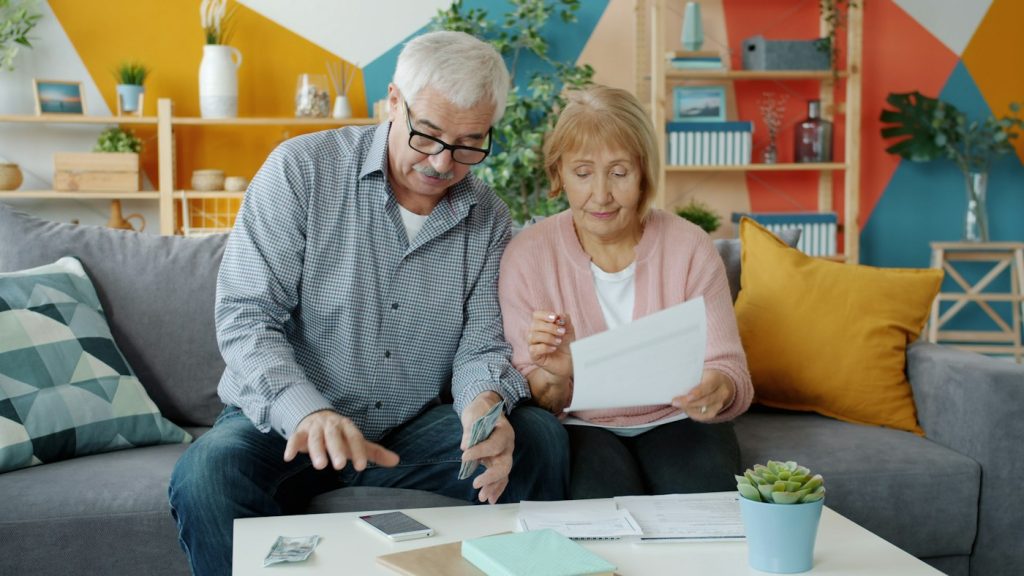 Couple de retraités relisant des documents d'assurance à leur table